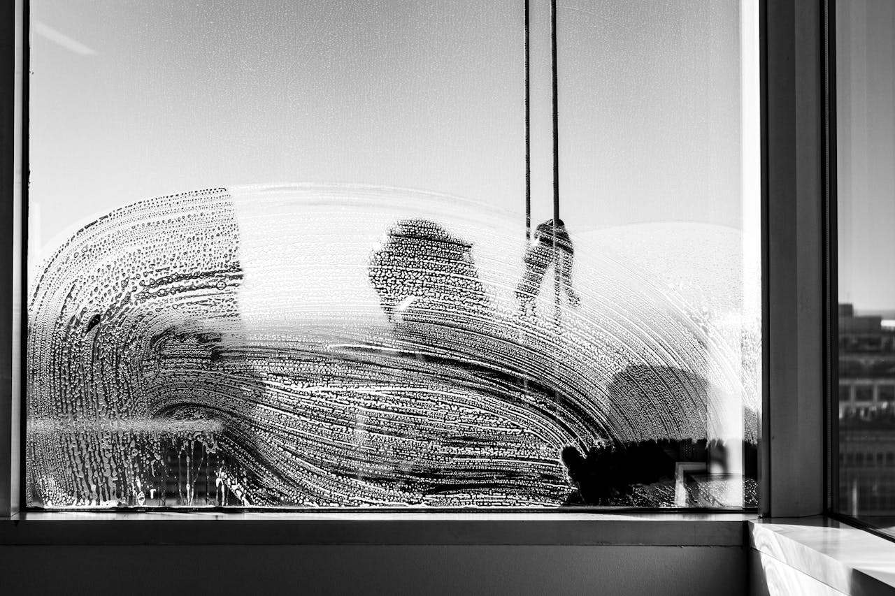 gallery-3 Black and white photo of a worker cleaning a glass window in urban Buenos Aires.
